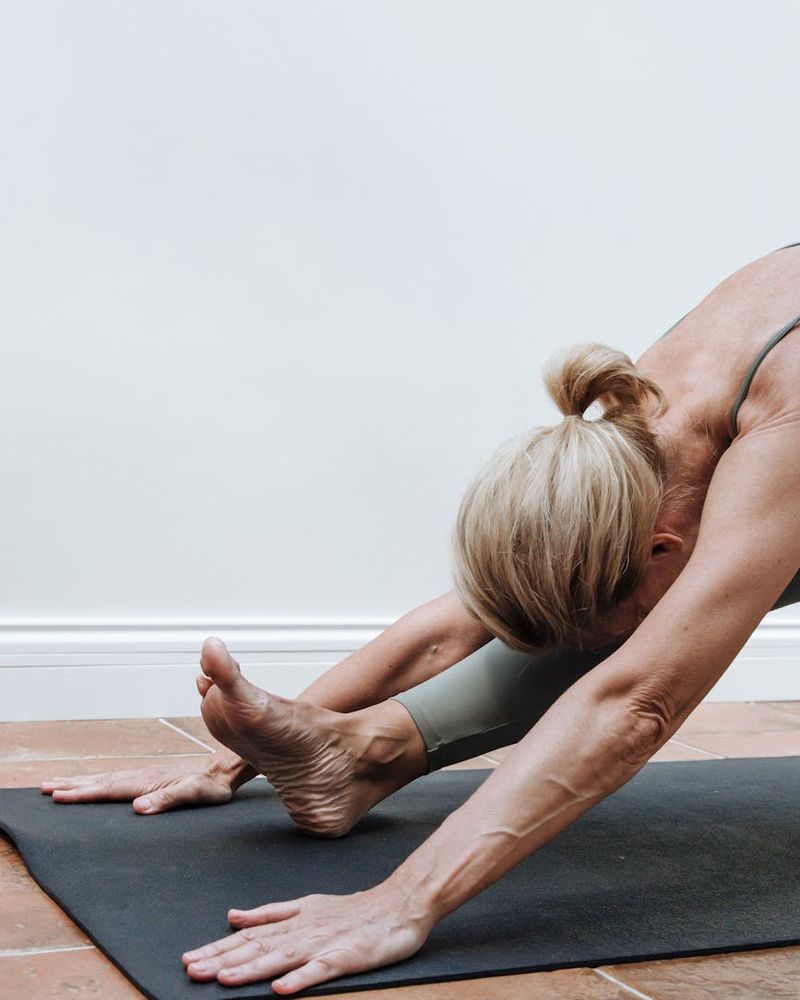 Person practicing slow yoga movements on a dark mat